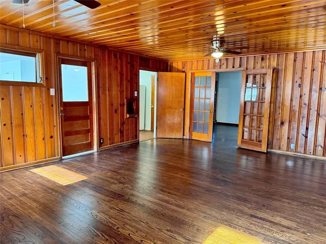 a view of an empty room with wooden floor and windows