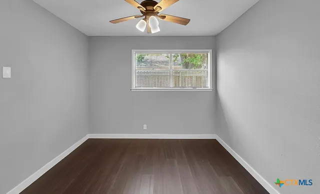 an empty room with wooden floor chandelier fan and windows