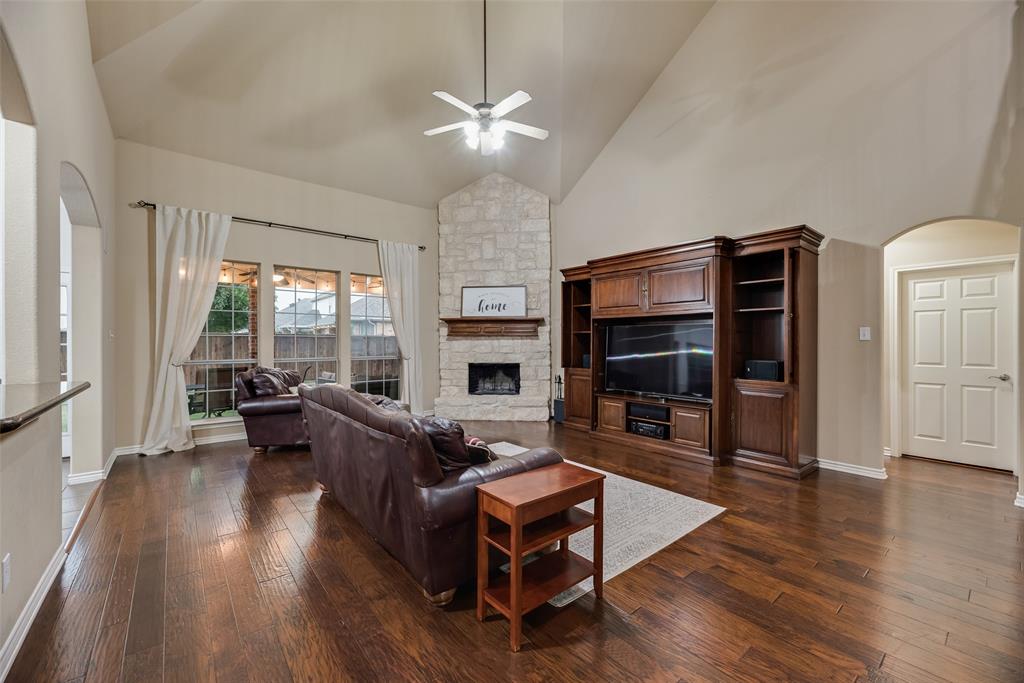 11920 Vienna Apple Road Fort Worth, TX 76244 - Photo 11 of 40 Expansive living room with hardwood floors, wood burning fireplace with gas starter, soaring vaulted ceilings and ceiling fan at 11920 Vienna Apple in Villages of Woodland Springs community in North Fort Worth