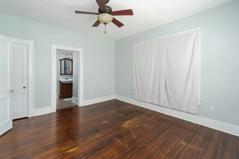an empty room with wooden floor closet and windows