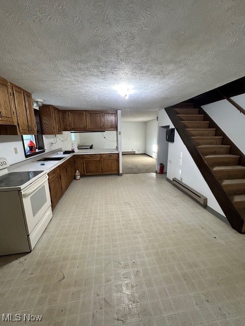 17510 Munn Road Chagrin Falls, OH 44023 - Photo 30 of 35 Kitchen with white electric range, light countertops, baseboard heating, light floors, and brown cabinetry