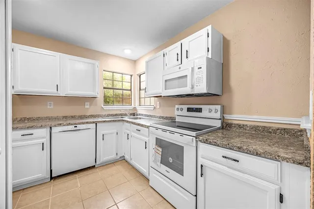 a kitchen with granite countertop white cabinets and white appliances