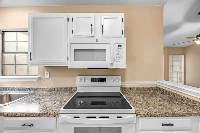 a kitchen with granite countertop white cabinets and white appliances