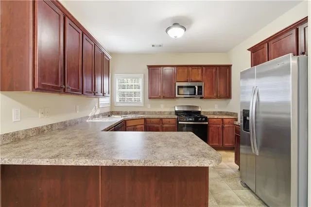 a kitchen with granite countertop wooden cabinets a refrigerator and a sink
