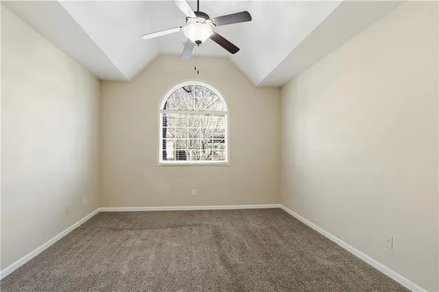 an empty room with a ceiling fan and windows