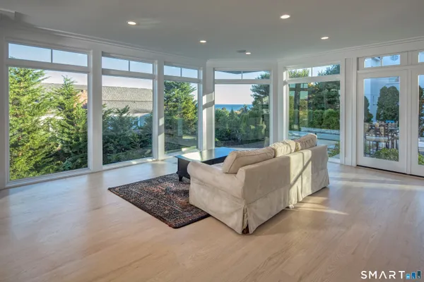 a living room with furniture large windows and wooden floor
