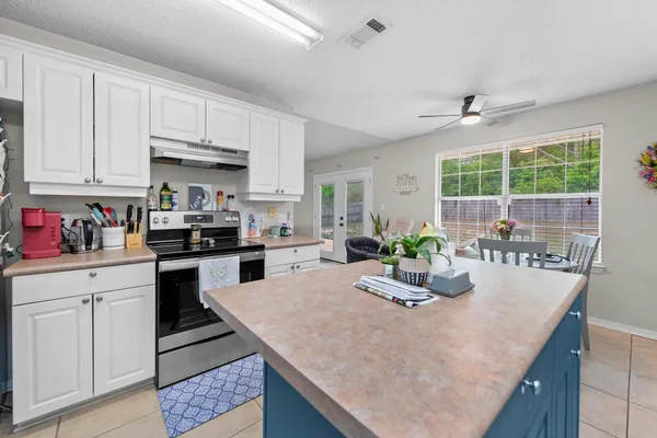 a kitchen with stainless steel appliances kitchen island granite countertop a table chairs in it and white cabinets