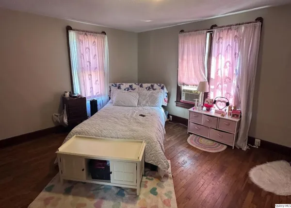 a spacious bedroom with a bed and wooden floor