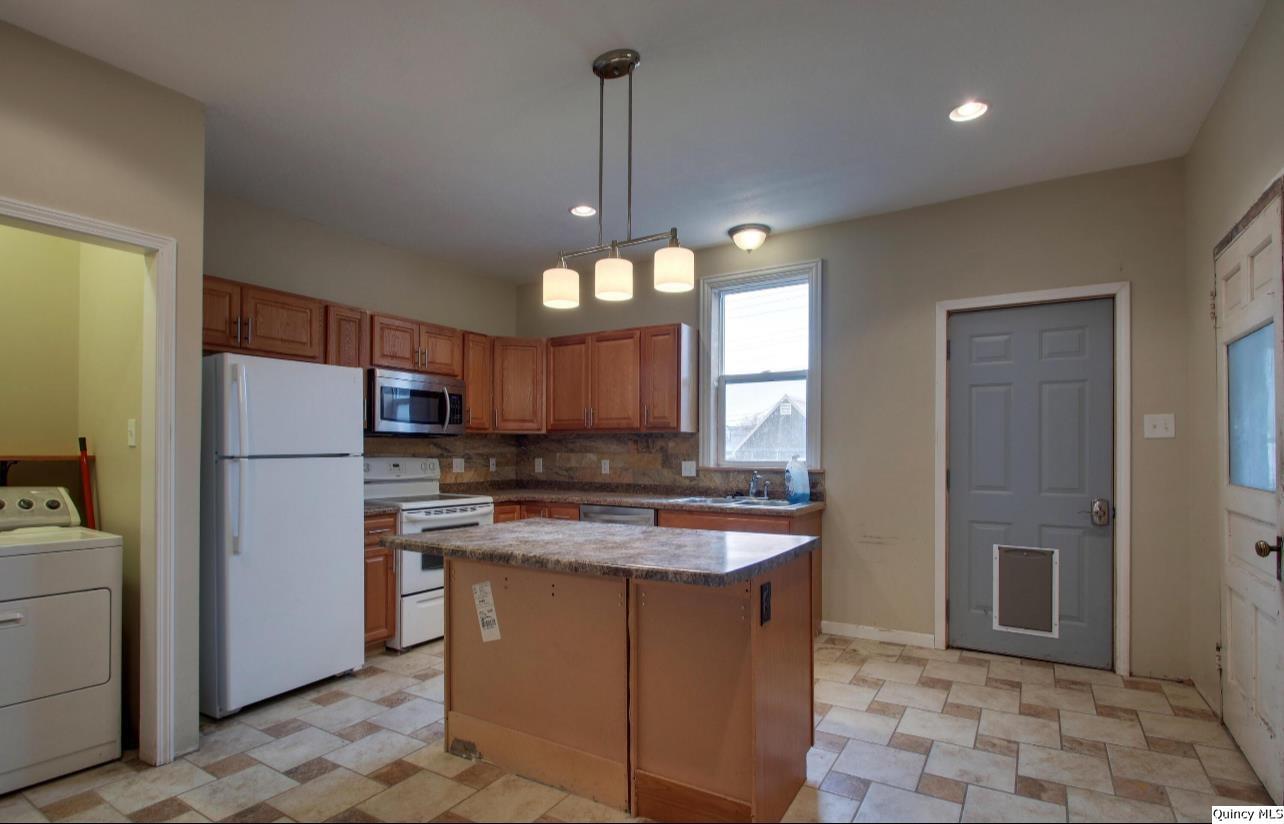 623 Payson Avenue Quincy, IL 62301 - Photo 7 of 13 a kitchen with stainless steel appliances granite countertop a sink a refrigerator a stove a washer dryer and a dining table
