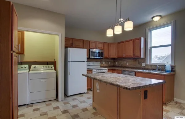 a kitchen with stainless steel appliances granite countertop a sink a stove a refrigerator cabinets and a dining table