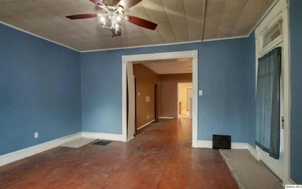 a view of an empty room with chandelier fan and a bathroom