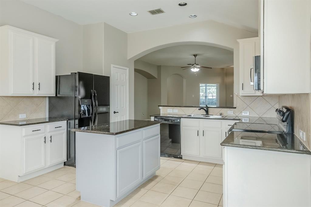 1109 Johnson City Avenue Forney, TX 75126 - Photo 13 of 40 a kitchen with granite countertop a sink stove and refrigerator