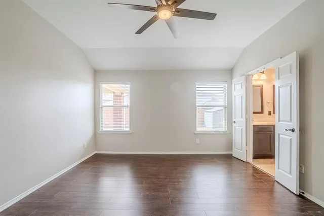 an empty room with wooden floor window and ceiling fan