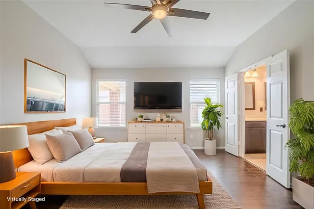 a bedroom with a bed television on desk and a window