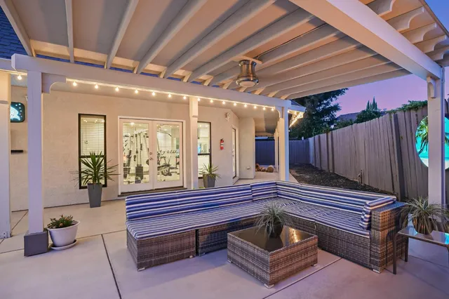 a patio with a table and chairs and potted plants