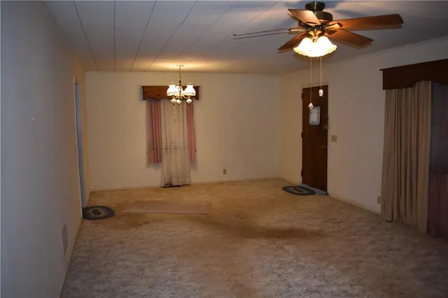 an empty room with a chandelier fan and a large window