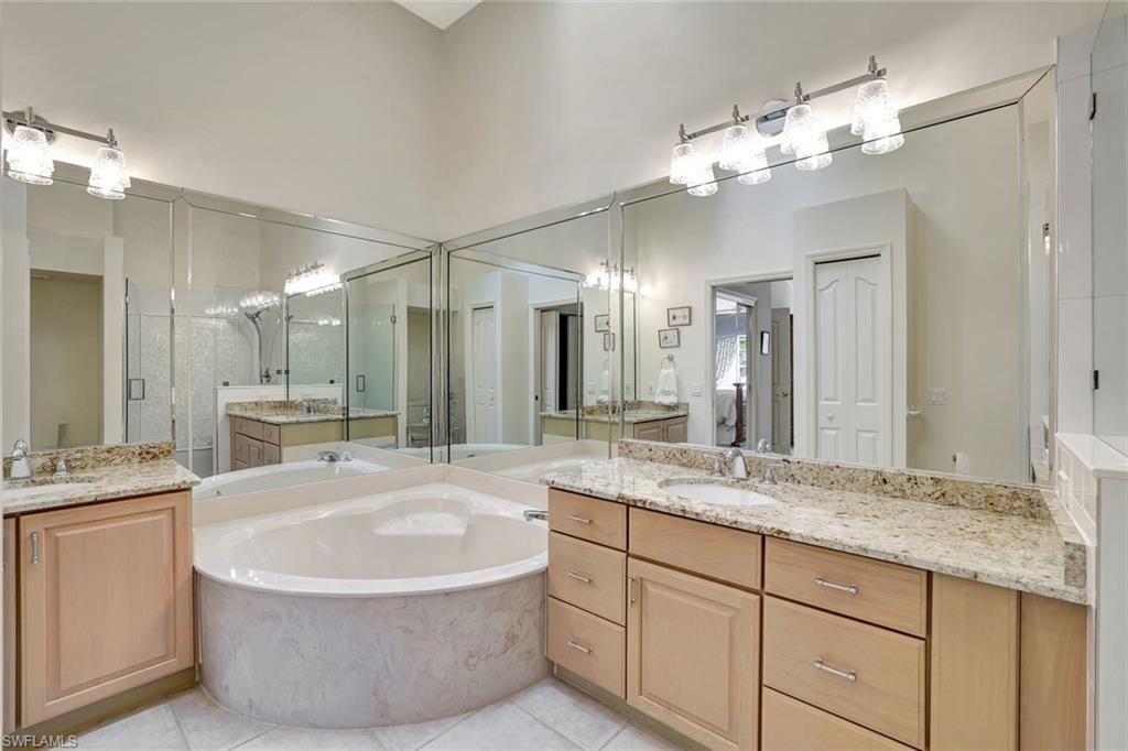 6200 Reserve Circle, Unit 404 Naples, FL 34119 - Photo 22 of 47 a bathroom with a granite countertop sink a large mirror and a bathtub