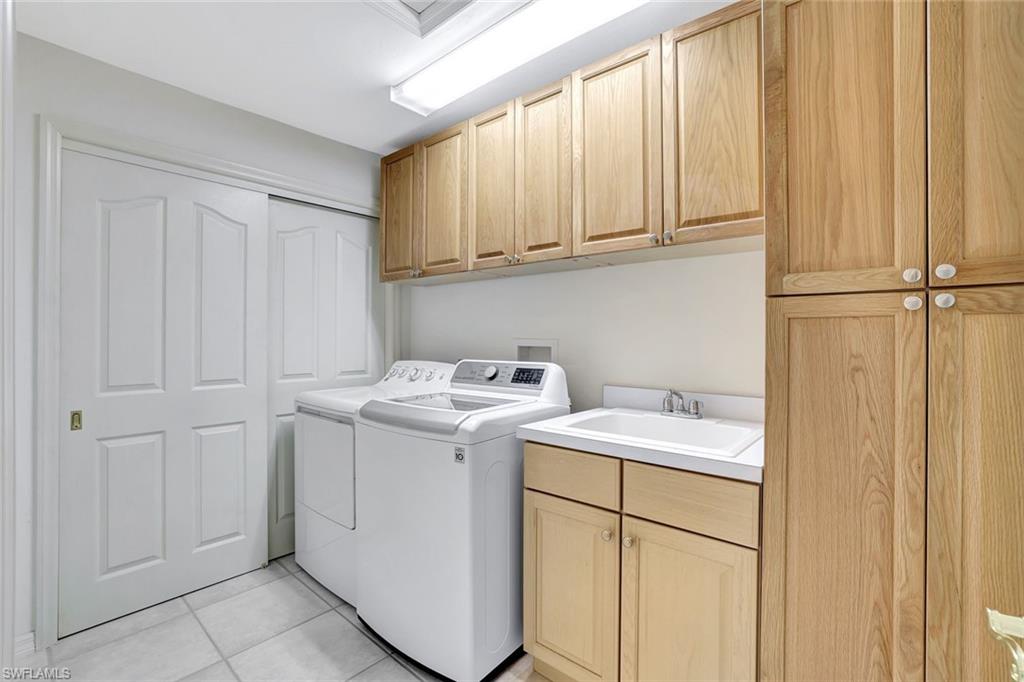 6200 Reserve Circle, Unit 404 Naples, FL 34119 - Photo 29 of 47 Laundry room with custom cabinet space, washing machine and dryer and sink.