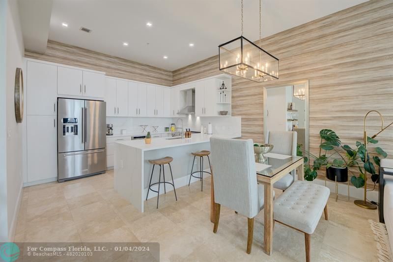 a kitchen with stainless steel appliances kitchen island granite countertop a refrigerator and a dining table