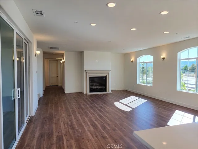 an empty room with wooden floor fireplace and windows