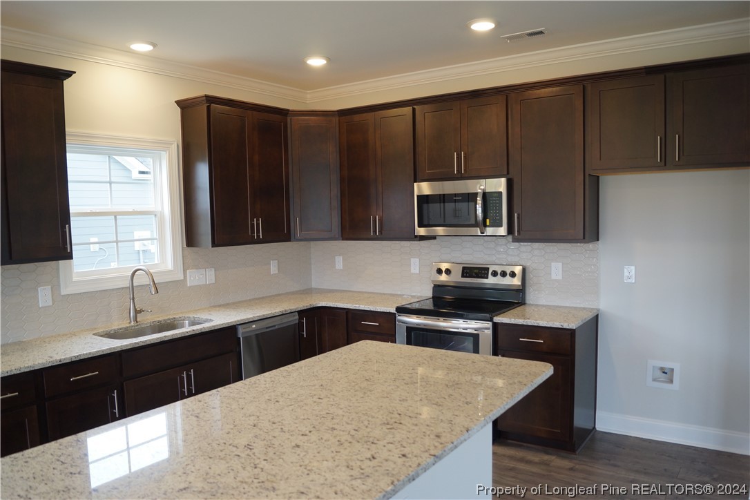 103 Grinnel Loop Sanford, NC 27332 - Photo 6 of 39 a kitchen with stainless steel appliances granite countertop a sink stove and microwave