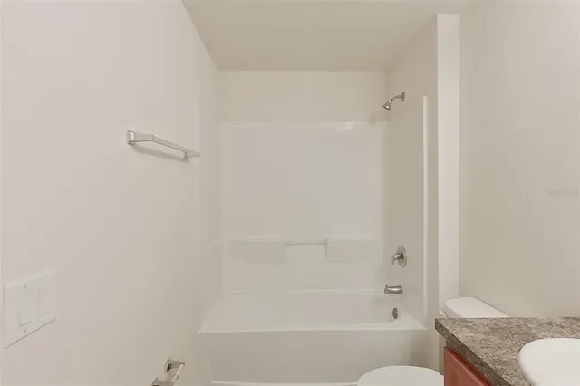 a bathroom with a granite countertop bathtub shower and toilet