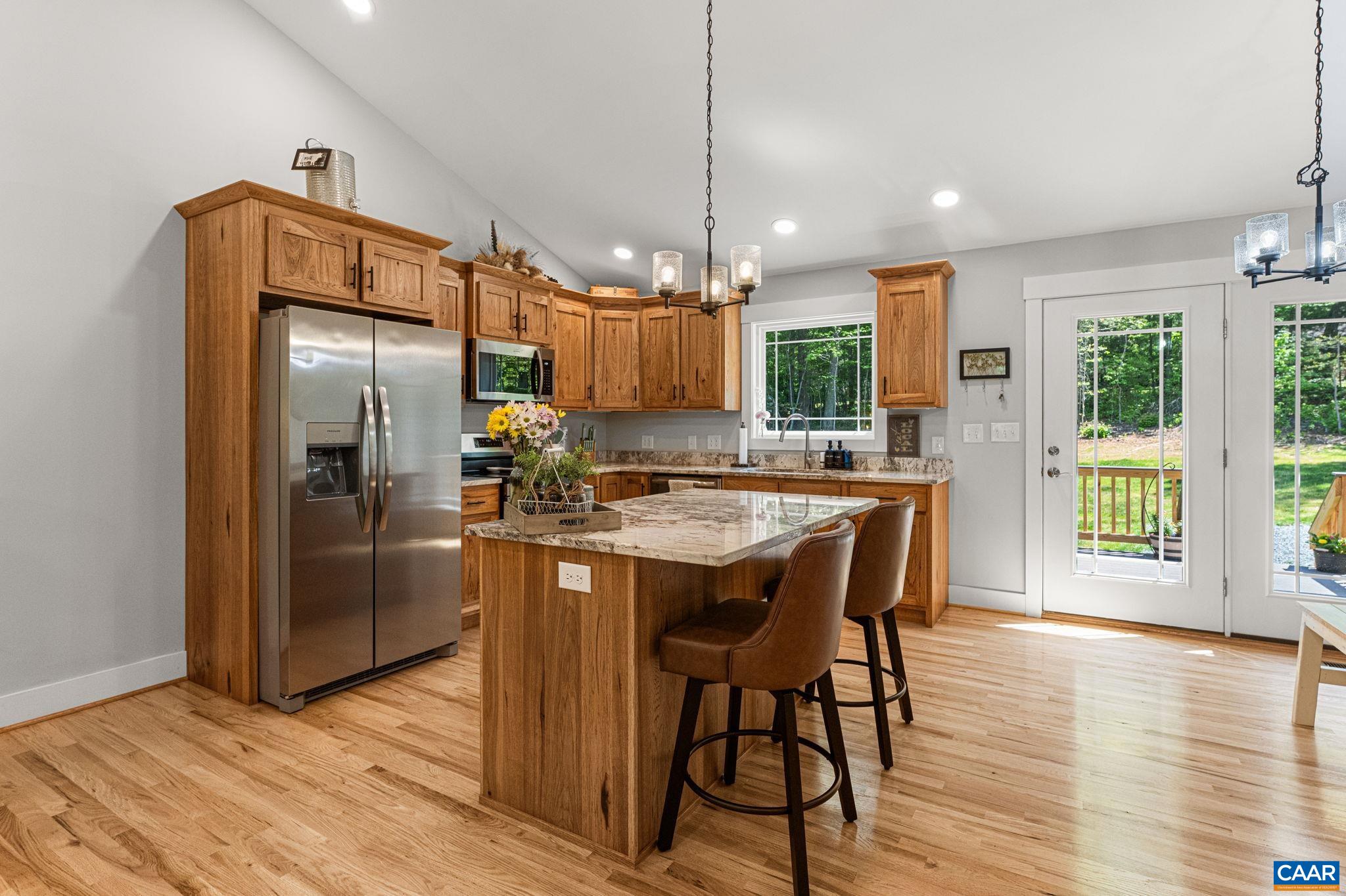 230 Fox Hollow Road Ruckersville, VA 22968 - Photo 13 of 42 a kitchen with stainless steel appliances granite countertop a refrigerator a sink dishwasher a stove and a dining table with wooden floor