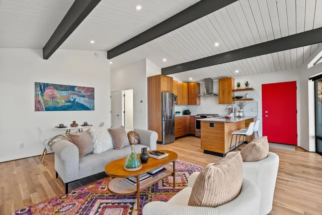 a living room with furniture kitchen view and a large window