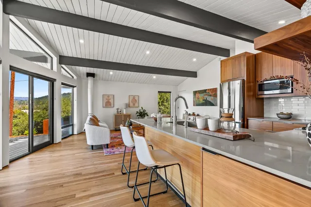 a living room with stainless steel appliances kitchen island granite countertop a table chairs and a large window