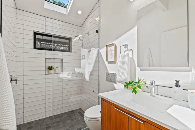 a bathroom with a granite countertop sink a toilet a mirror and shower