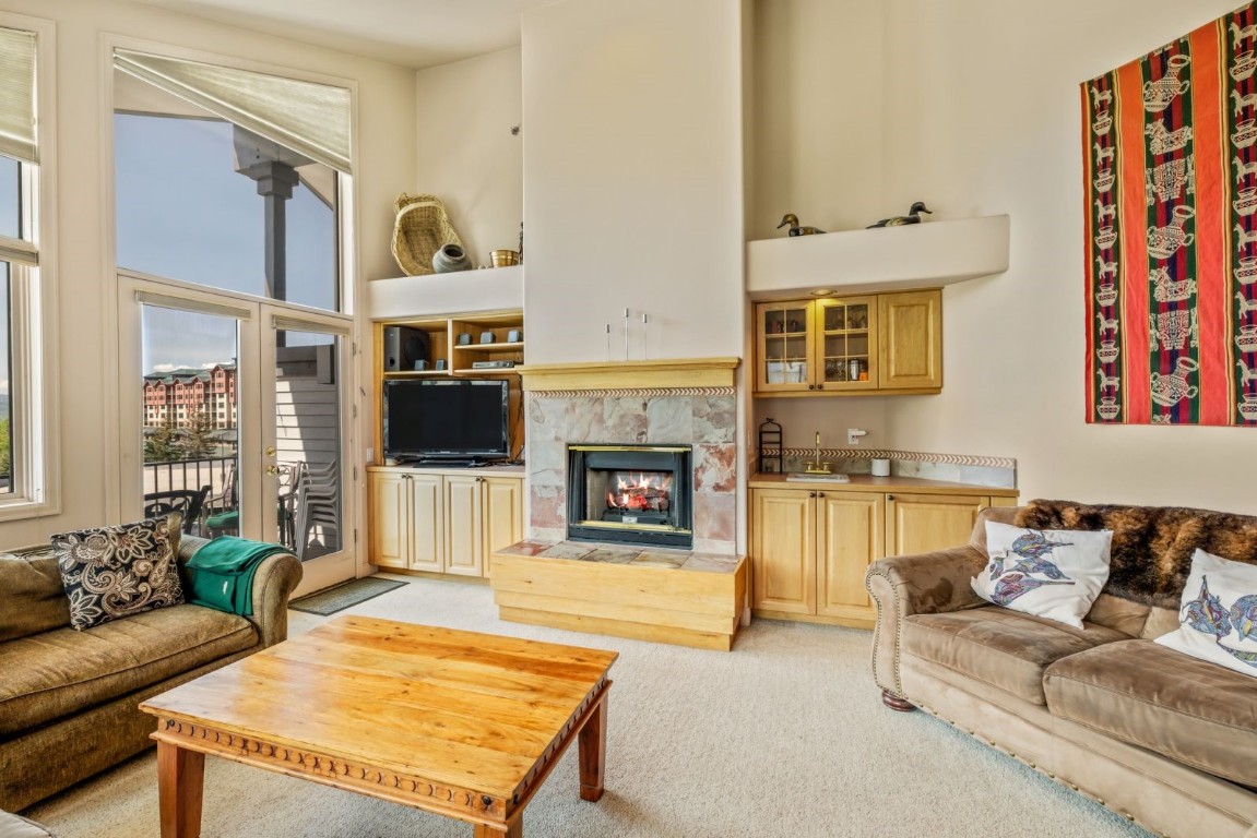 1724 Ski Time Square Drive, Unit R5 Steamboat Springs, CO 80487 - Photo 3 of 19 Living room with light colored carpet, a fireplace, and a towering ceiling