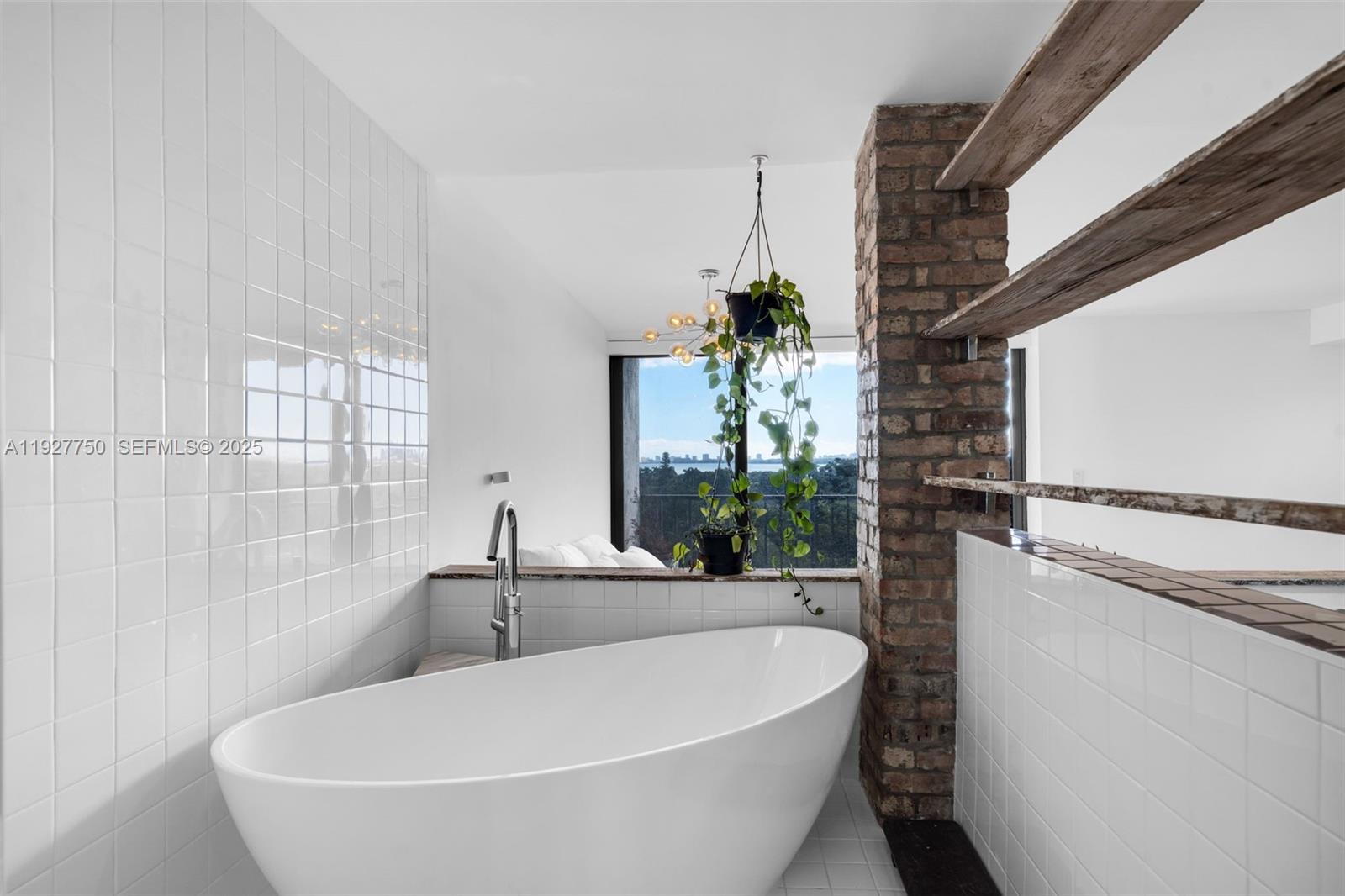 5701 Biscayne Boulevard, Unit PH9 Miami, FL 33137 - Photo 26 of 40 a white bath tub sitting in a bathroom next to a window