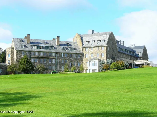a view of a big building with a big yard and large trees
