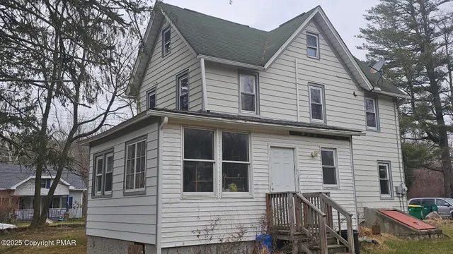 a view of a house with a yard and large tree