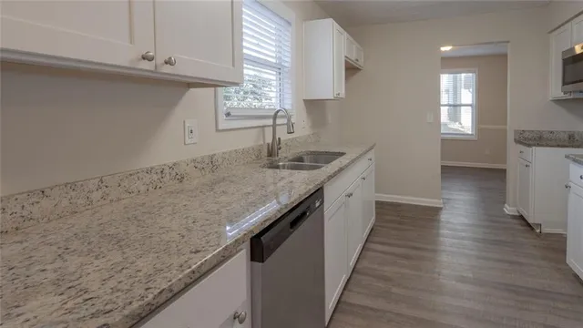 a view of a hallway with wooden floor and a bathroom