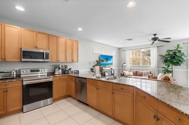 a kitchen with stainless steel appliances granite countertop white cabinets sink and window