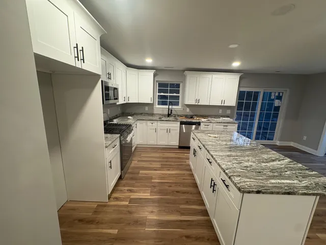a kitchen with granite countertop a refrigerator and a stove top oven