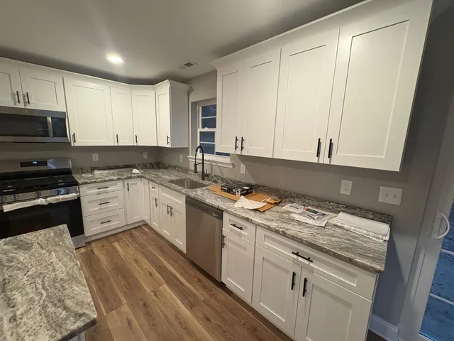 a kitchen with granite countertop a sink a stove and cabinets