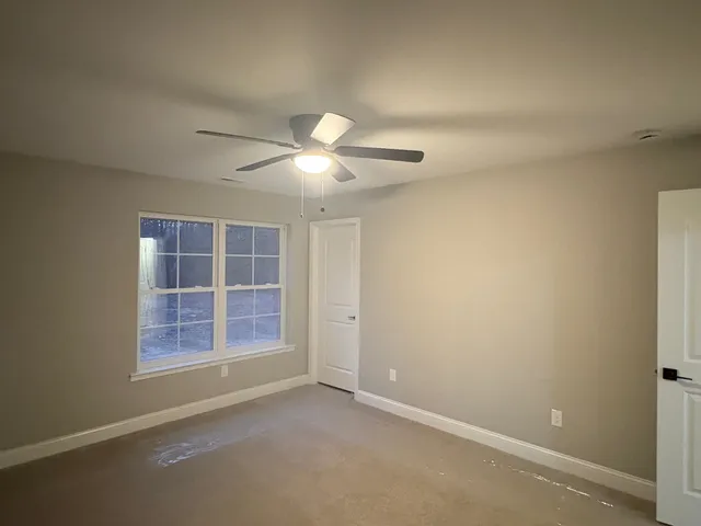 an empty room with windows and chandelier fan