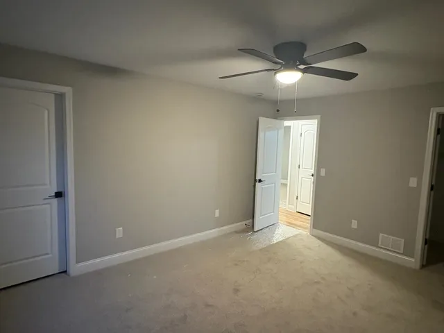 an empty room with closet and a chandelier fan