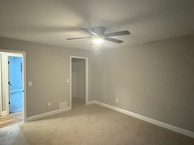 an empty room with a fan & a window