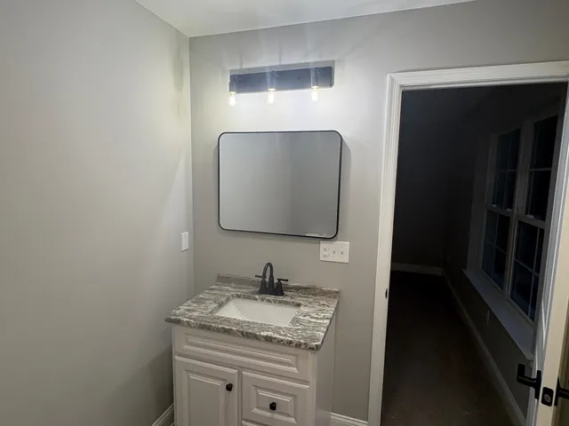 a bathroom with a granite countertop sink and a mirror