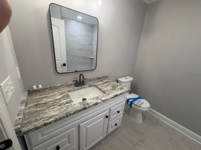 a bathroom with a granite countertop sink and a mirror
