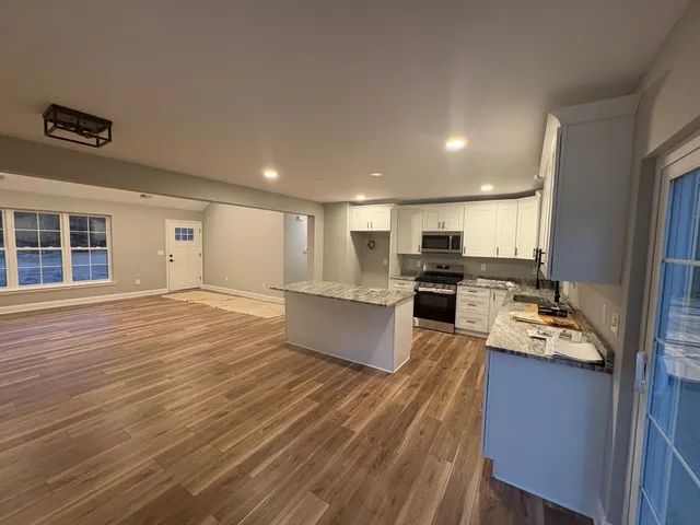 a large kitchen with stainless steel appliances granite countertop a large counter top a stove and a refrigerator