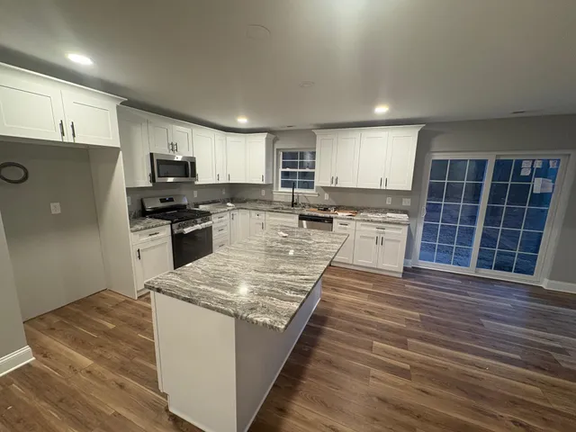 a large kitchen with stainless steel appliances granite countertop a stove a sink and a refrigerator