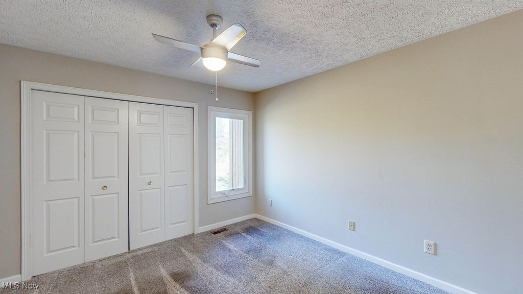 1426 Loop Road, Unit 1426 Kent, OH 44240 - Photo 21 of 40 Guest bedroom with carpet flooring, a textured ceiling, a ceiling fan, and a closet.
