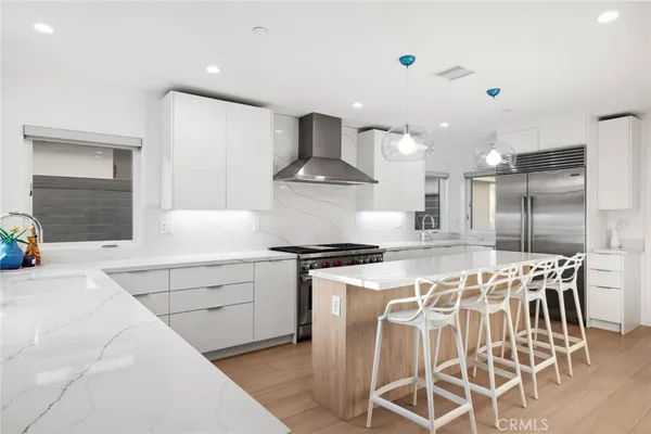 a kitchen with stainless steel appliances a stove a sink island white cabinetry and chairs