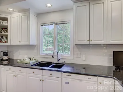 a kitchen with granite countertop white cabinets sink and window