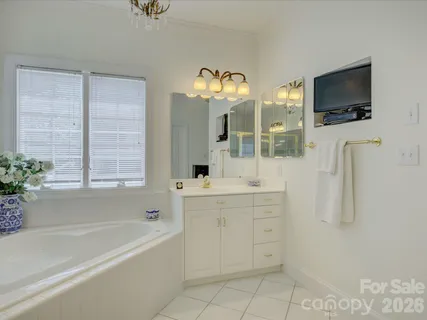 a bathroom with a double vanity sink a mirror a window and a bathtub