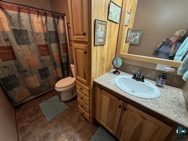 9015 Arkola Road Cotton, MN 55724 - Photo 10 of 21 Bathroom featuring vanity, backsplash, tile patterned flooring, and toilet